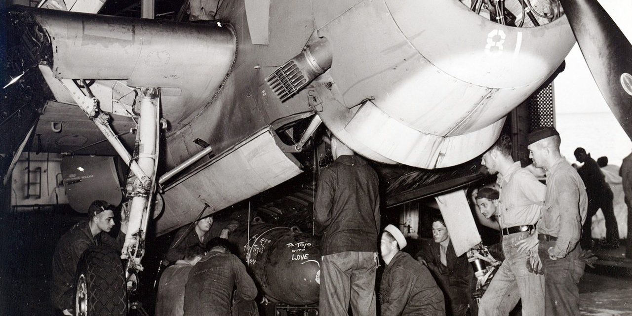 Ordinancemen loading a 1,000-pound bomb into the bombay of a TBM-1C aboard USS Intrepid, 1943-1945; note flame…