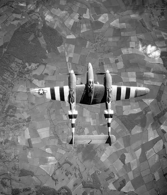 Top view of a P-38 Lightning aircraft in flight over the English countryside, June 1944.