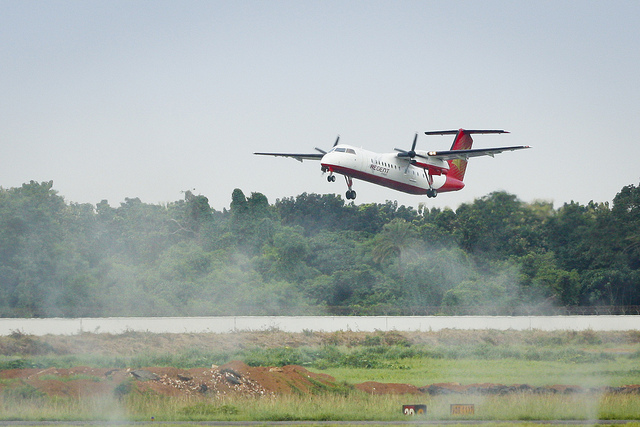 Regent Airways Bombardier Dash 8-Q311 S2-AHB takes off using Runway 14 over smoke that has been created from the…